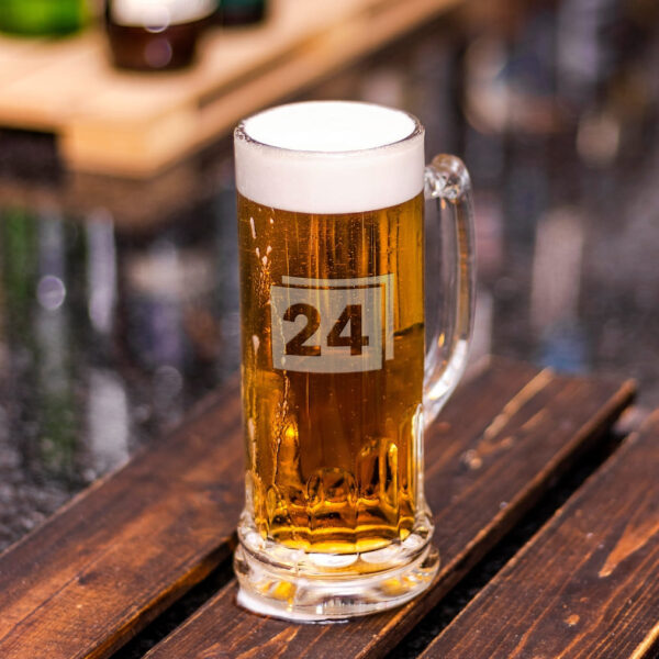 Bierkrug mit Gravur „24“ und Schaumkrone auf Holztisch