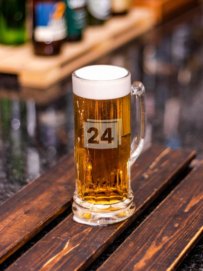 Bierkrug mit Gravur „24“ und Schaumkrone auf Holztisch