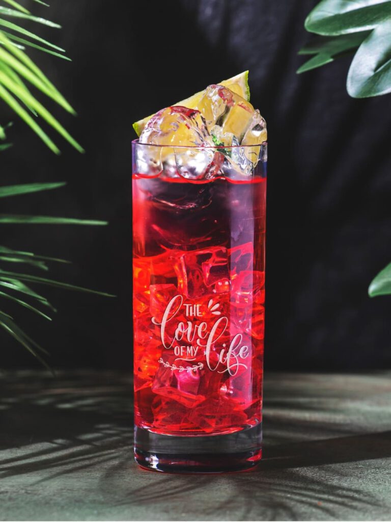 Longdrinkglas mit rotem Getränk, Eis und Limette, Gravur „The love of my life“