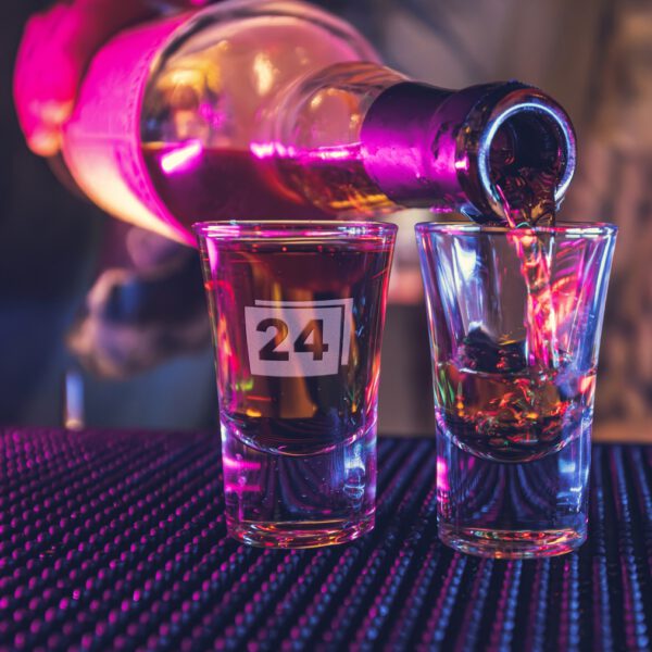 Zwei Schnapsgläser, eines mit Gravur „24“, wird befüllt