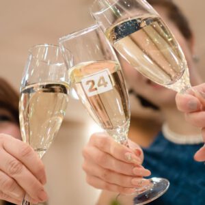 Sektgläser mit Gravur „24“, Personen stoßen an