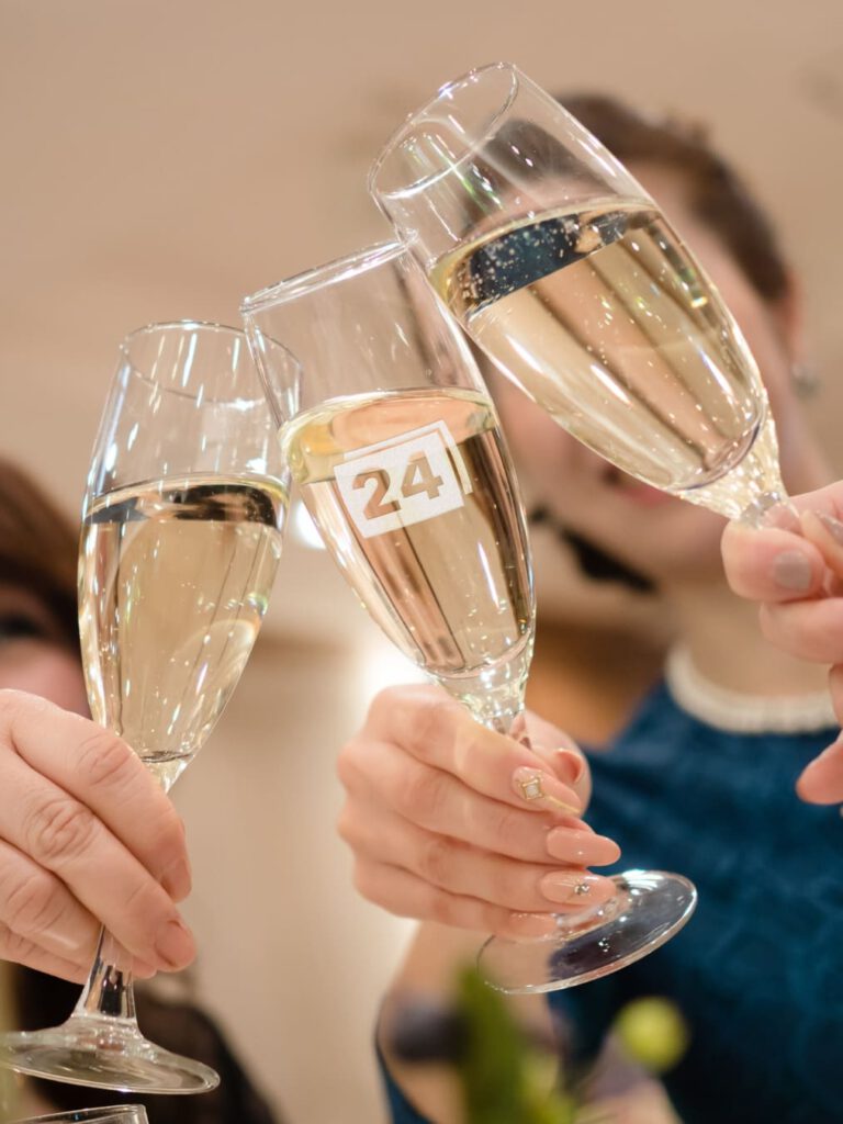 Sektgläser mit Gravur „24“, Personen stoßen an