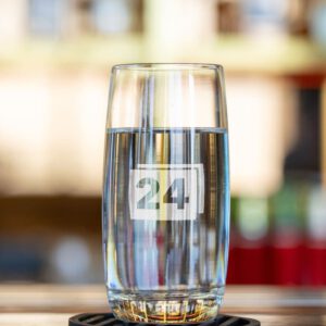 Wasserglas mit Gravur „24“ auf Theke mit hellem Hintergrund