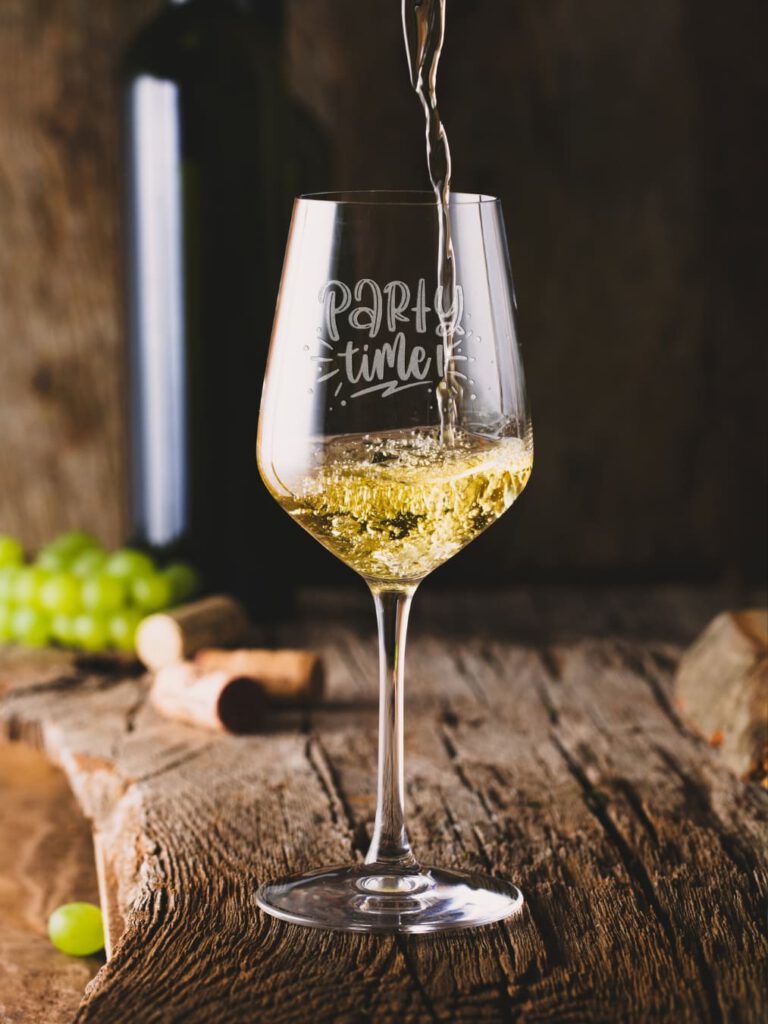 Weißweinglas mit Gravur „Party time“, wird gerade befüllt