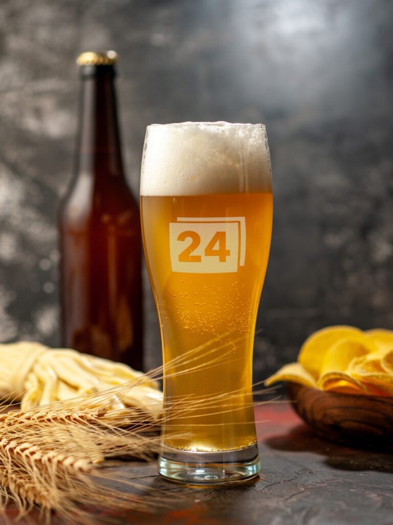 Weizenglas mit Gravur „24“, gefüllt mit Bier und Schaumkrone